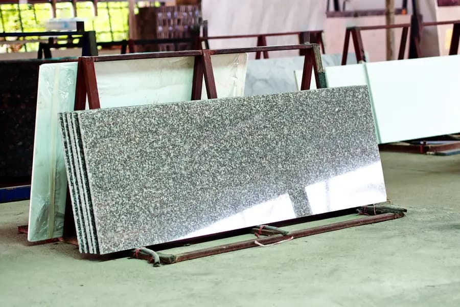 Cut stone and quartz slabs standing on racks in a fabrication shop.